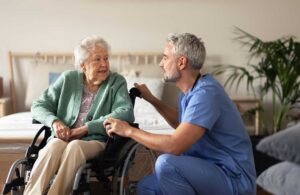 An older adult and family member sitting together at a kitchen table, discussing paperwork and sharing a warm conversation.